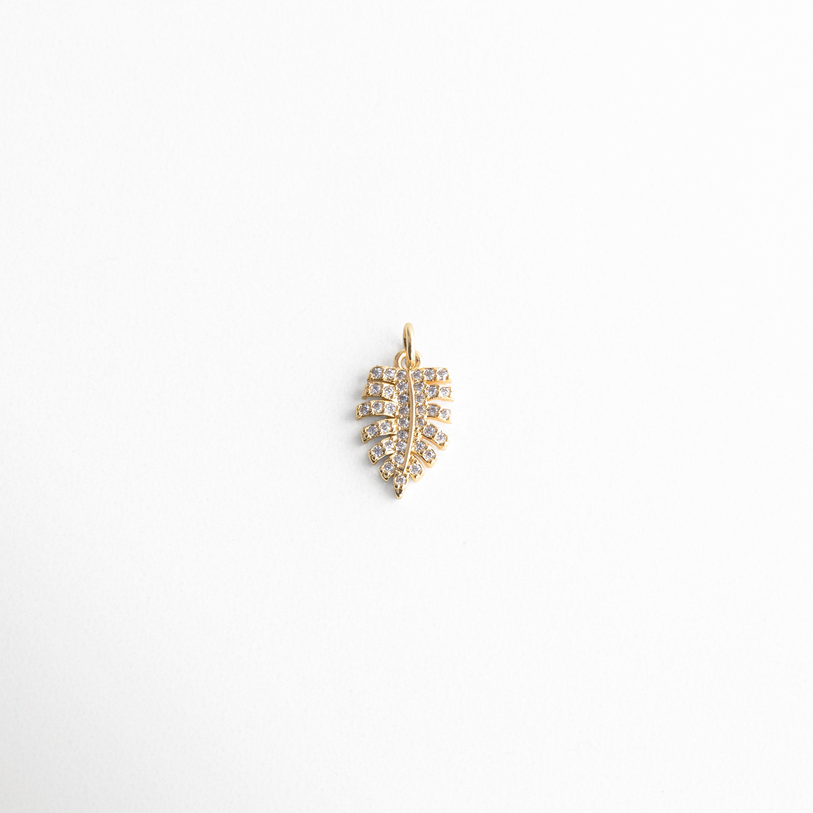 Charm dorado en forma de hoja con incrustaciones de zirconias, diseño delicado y elegante que refleja la belleza de la naturaleza, ideal para quienes buscan un toque brillante y sofisticado en su look diario