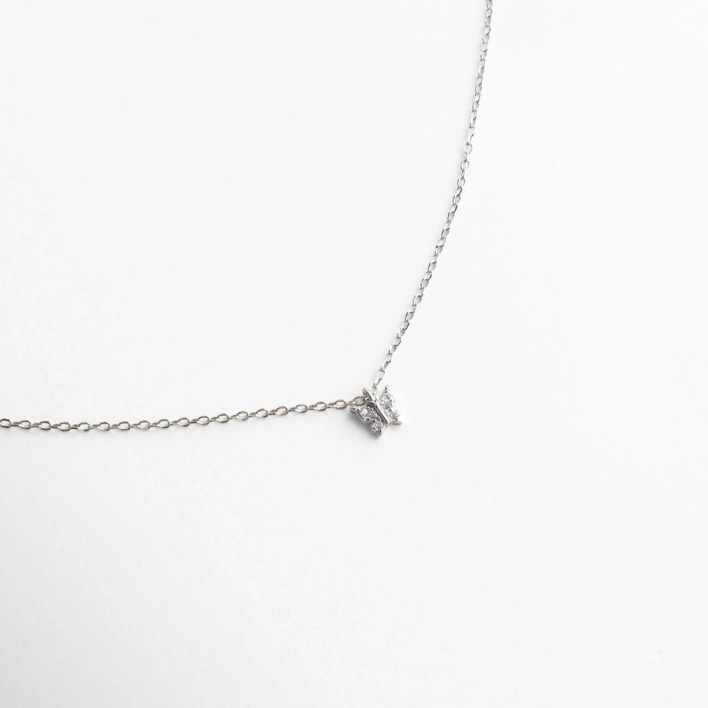 Collar plateado con dije pequeño en forma de mariposa con zirconias brillantes, símbolo de delicadeza y renovación.