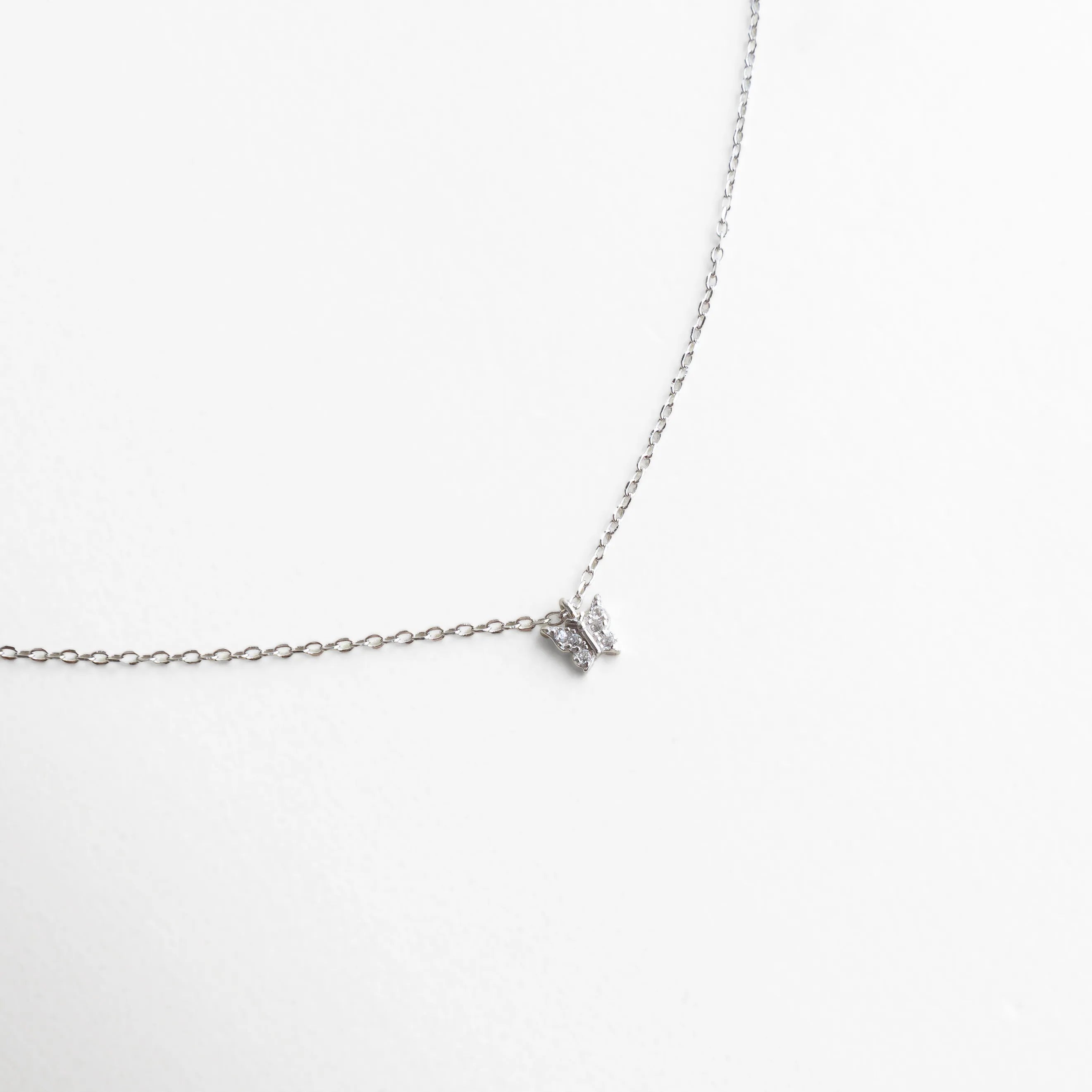 Collar plateado con dije pequeño en forma de mariposa con zirconias brillantes, símbolo de delicadeza y renovación.