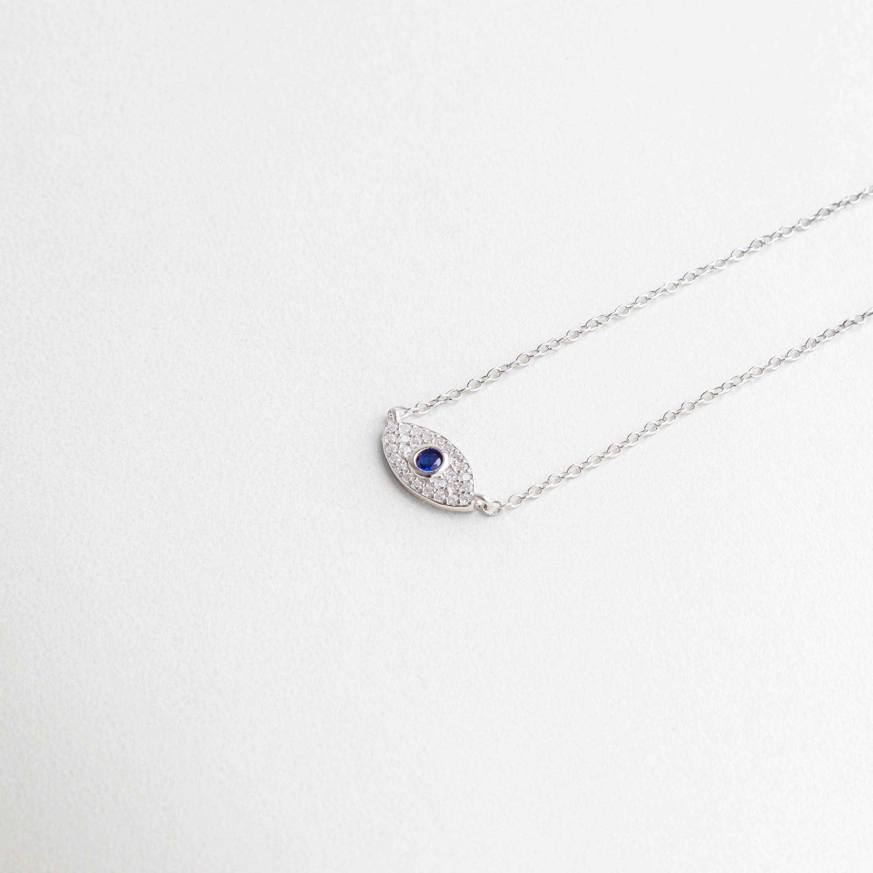 dije de ojo turco en plata ley 925, incrustaciones de zirconias brillantes, diseño delicado con acabado pulido, equilibrio entre misticismo y elegancia, detalle central que atrae miradas