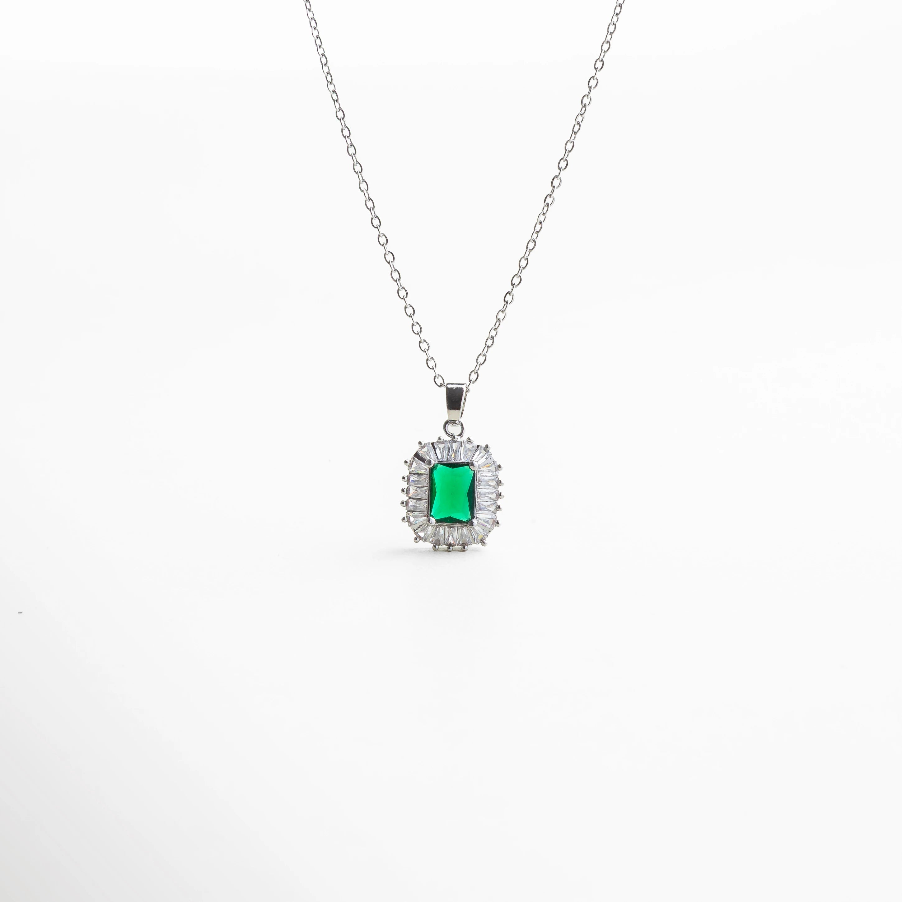 Collar plateado con dije de piedra verde rectangular estilo esmeralda, rodeado de destellos claros, diseño clásico ideal para ocasiones especiales.