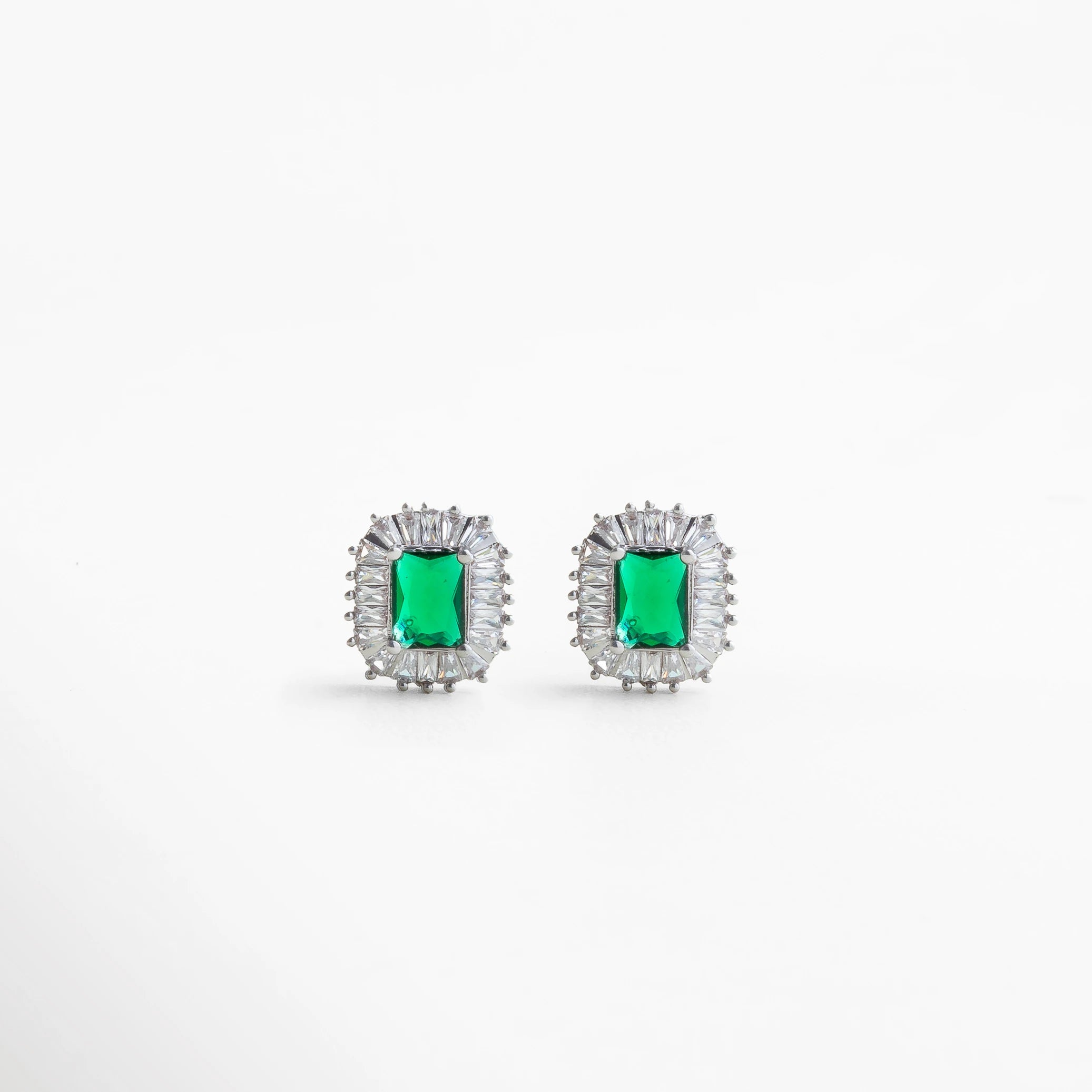 Aretes plateados con piedra verde rectangular y halo brillante, joyería elegante de inspiración clásica para looks formales o de noche.