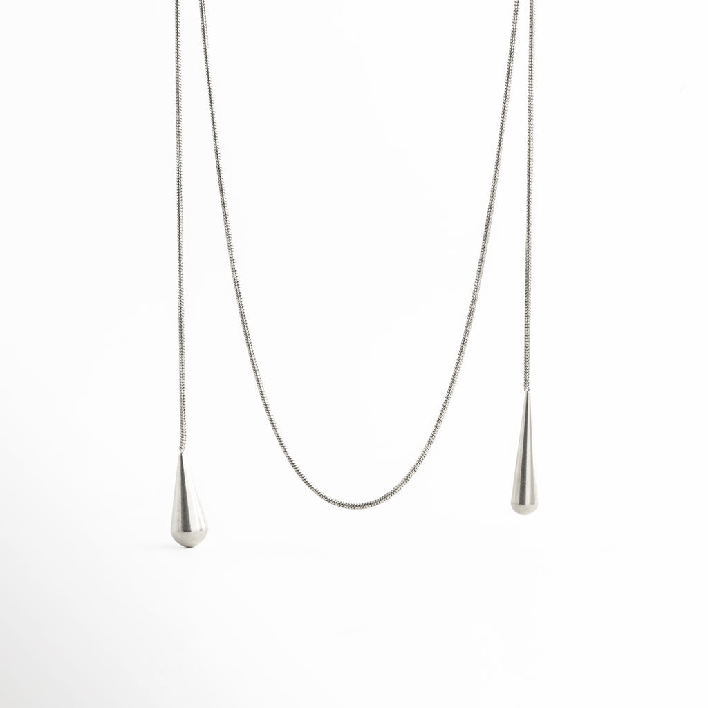 detalle de cadena en collar lariat, collar largo con cadena fina elegante, textura de cadena joyería minimalista, collar estilo lariat acabado sofisticado, joya moderna detalle de cadena