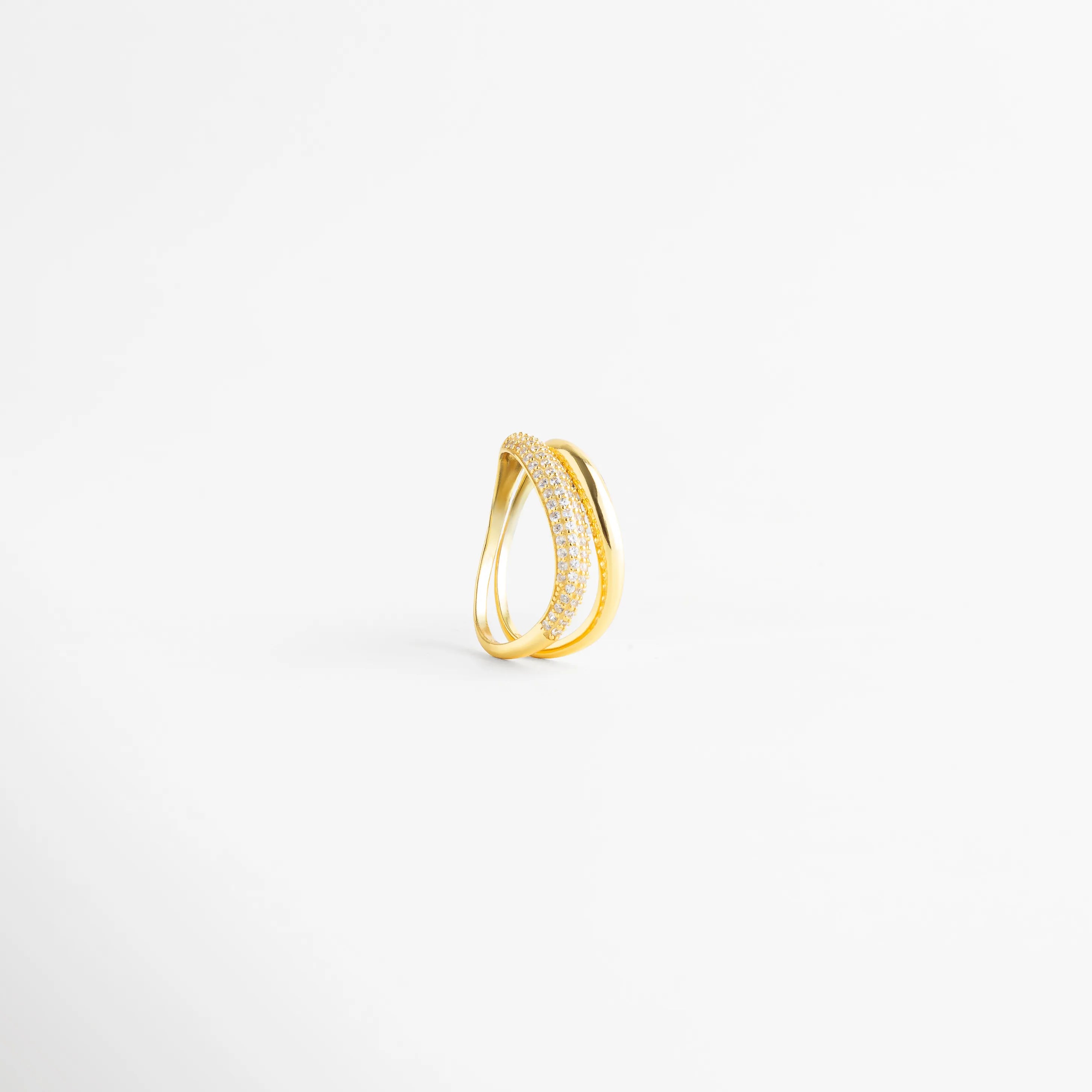 Vista lateral de anillo de plata 925 mostrando la curvatura y el diseño abierto, Perfil de anillo dorado con banda de diamantes AB y banda lisa pulida, Detalle constructivo de sortija de plata ley 925 con acabado de lujo, Estructura de anillo de doble hilo con incrustaciones frontales de diamantes, Perspectiva de perfil de anillo moderno con piedras preciosas artificiales.