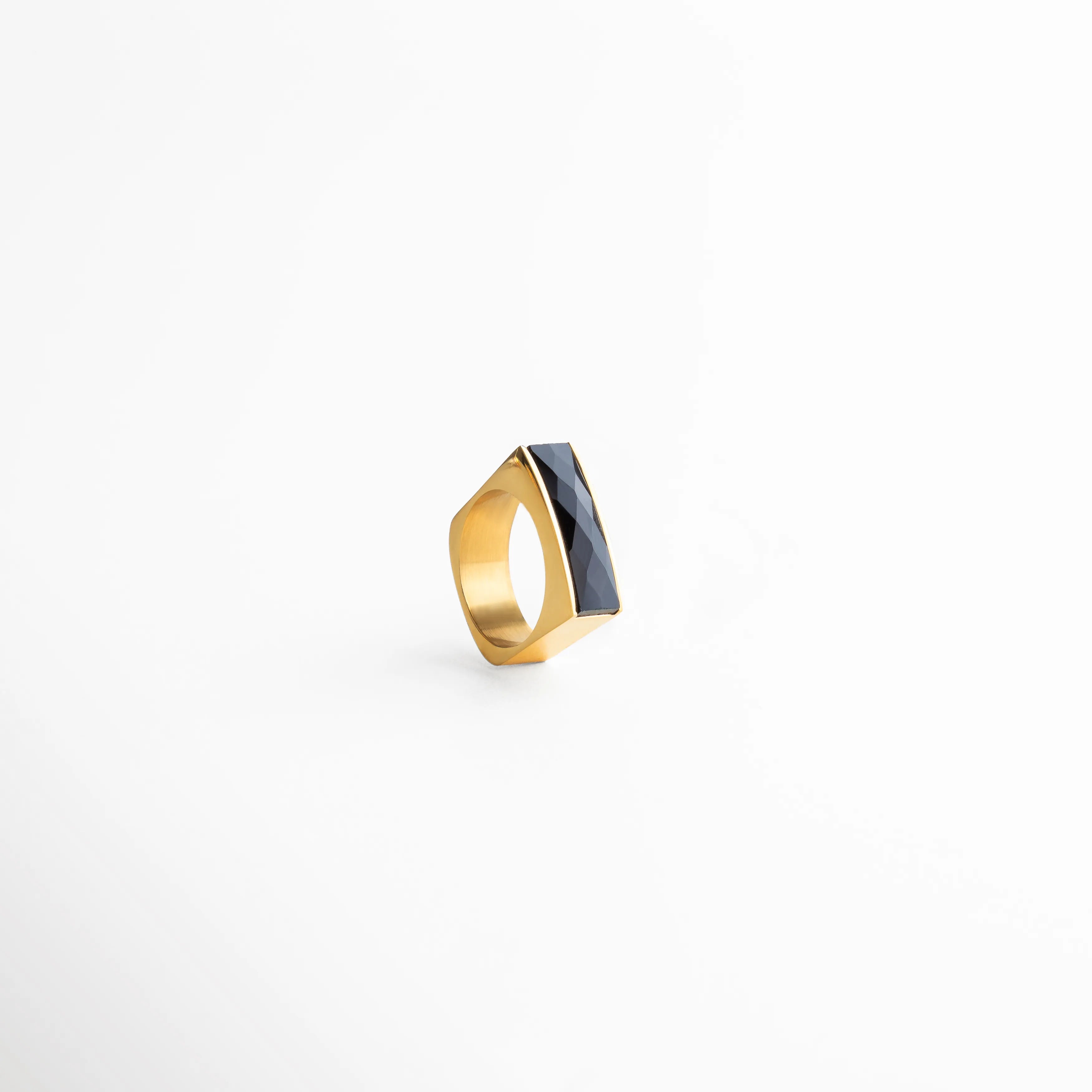 Vista en ángulo del anillo dorado con detalle negro, diseño contemporáneo y acabado pulido ideal para looks modernos.