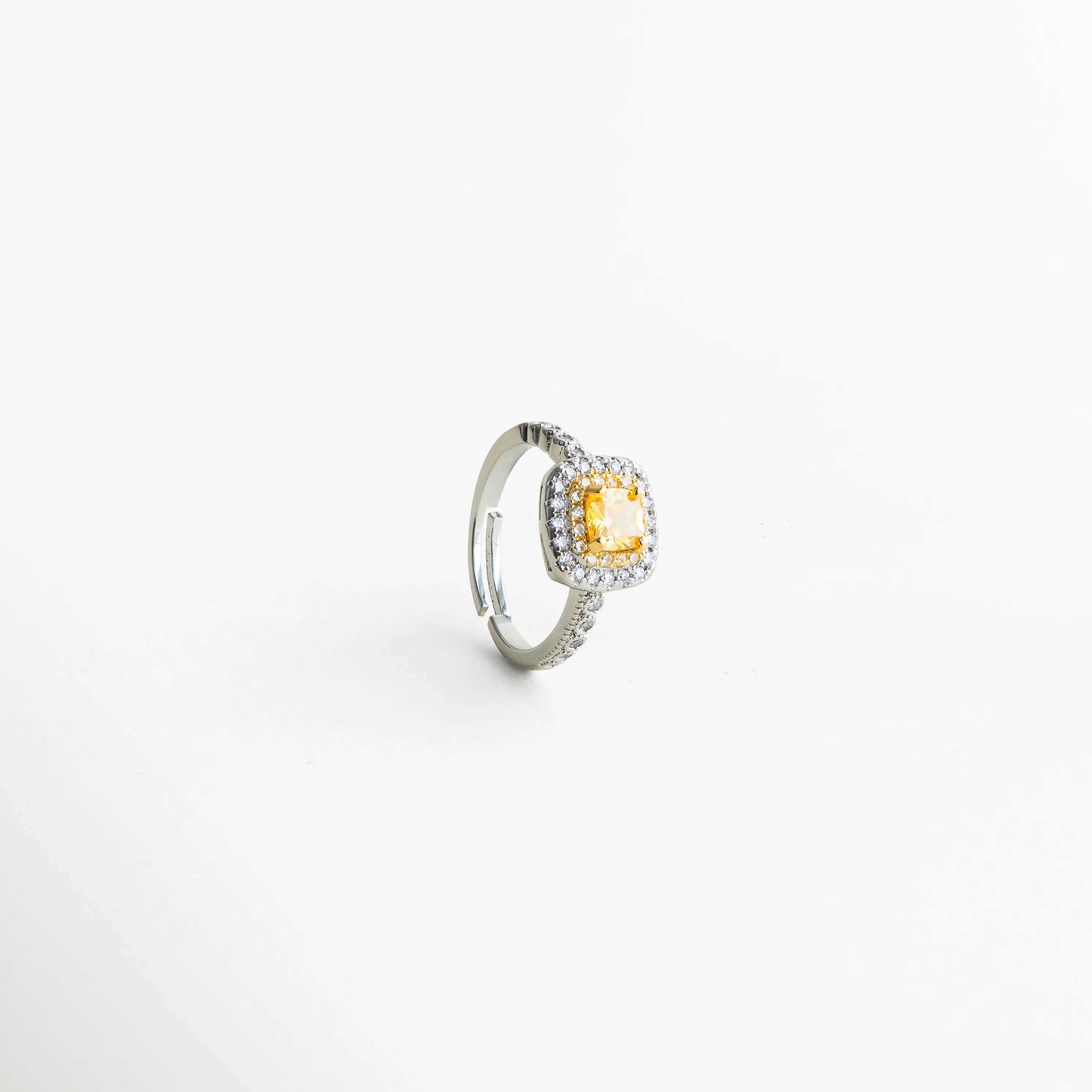 anillo plateado con piedra amarilla y halo brillante, joyería elegante con zirconias y diseño refinado, anillo femenino ideal para looks sofisticados, pieza de joyería con estética chic y moderna, anillo con detalles brillantes y proporciones delicadas, joyería contemporánea con toque europeo