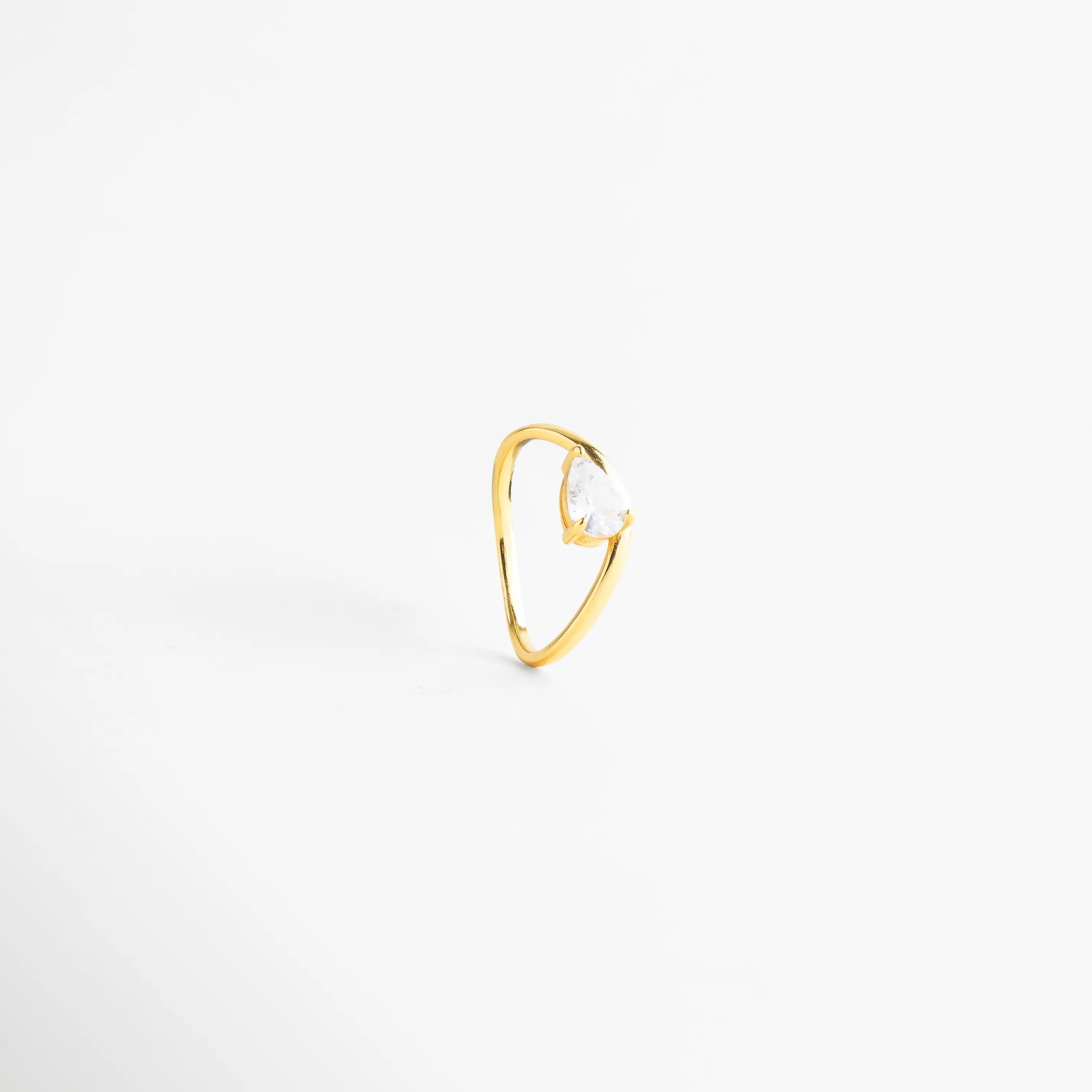 Vista trasera de la banda de plata 925 mostrando el acabado uniforme, Detalle de la curvatura del anillo dorado en perspectiva tres cuartos, Anillo minimalista de plata ley con piedra brillante visto desde atrás, Calidad del acabado enchapado en oro sobre base de plata ley 925, Sortija de diseño fluido con zirconia de alta claridad y brillo.