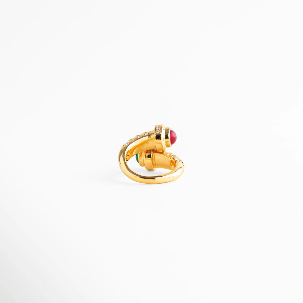 anillo dorado visto en ángulo con piedra roja, anillo elegante con diseño envolvente moderno, joyería dorada con brillo sofisticado, anillo statement para look nocturno, anillo de lujo contemporáneo, anillo dorado con carácter fuerte