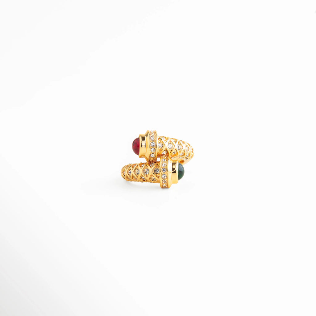 anillo dorado con diseño envolvente y piedra roja, anillo statement dorado con detalle brillante, anillo elegante con acento rojo central, joyería dorada sofisticada estilo moderno, anillo llamativo de acabado pulido, anillo dorado con diseño artístico
