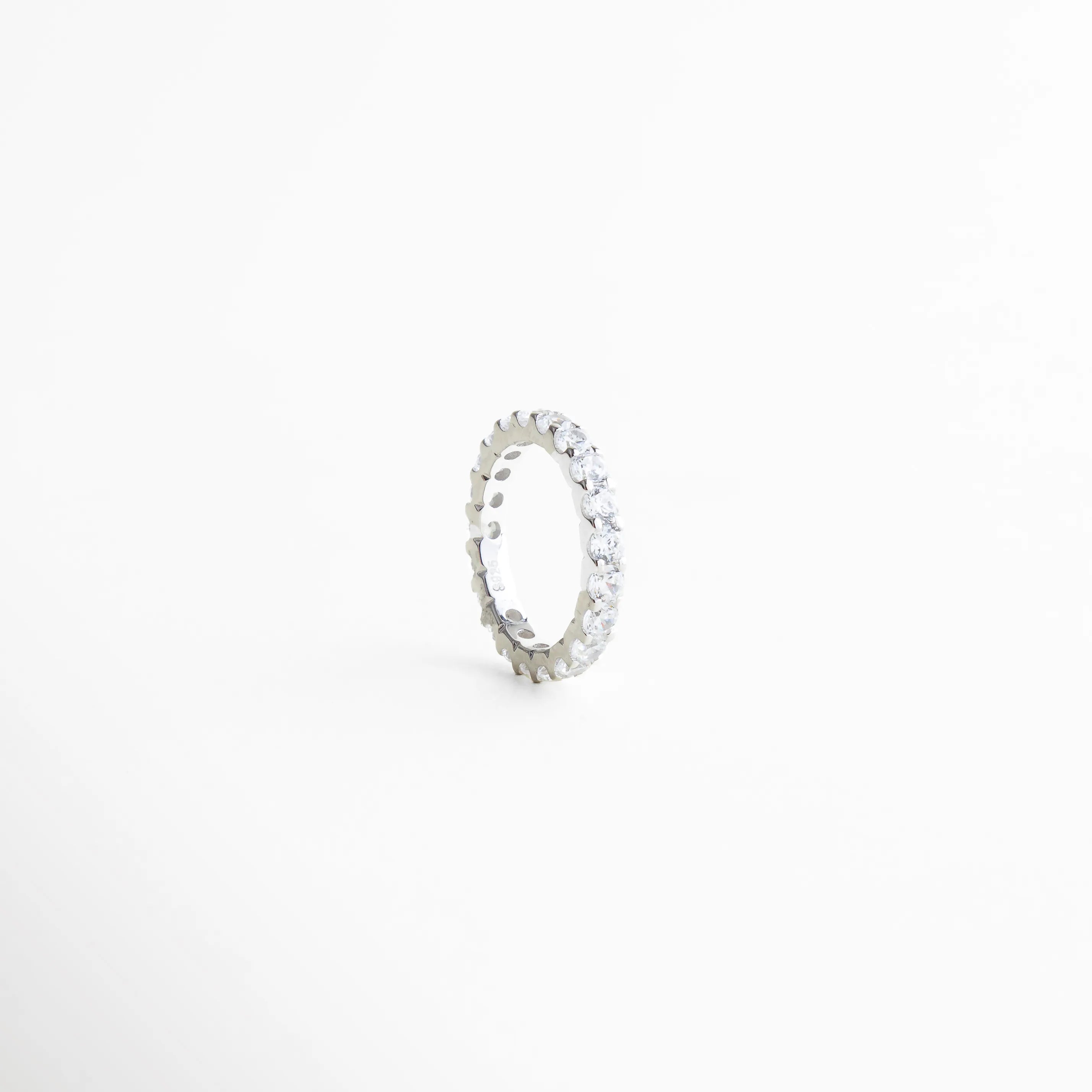 detalle de zirconias engastadas en anillo, anillo churumbela con acabado pulido, joyería fina con brillo discreto, anillo delicado de diseño continuo, anillo elegante de estética refinada, anillo minimalista con zirconias