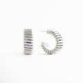 detalle de aretes hoops plateados acabado pulido, textura lisa en aretes chunky plateados, brillo metálico en aretes futuristas plateados, diseño voluminoso en aretes tipo aro plateados, acabado espejo en aretes statement