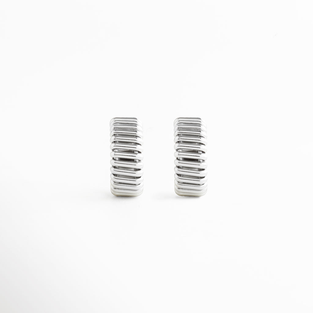 aretes hoops plateados chunky estilo futurista, aretes tipo aro statement plateados modernos, hoops plateados grandes joyería contemporánea, aretes chunky plateados diseño vanguardista, aretes de aro grueso plateados mujer