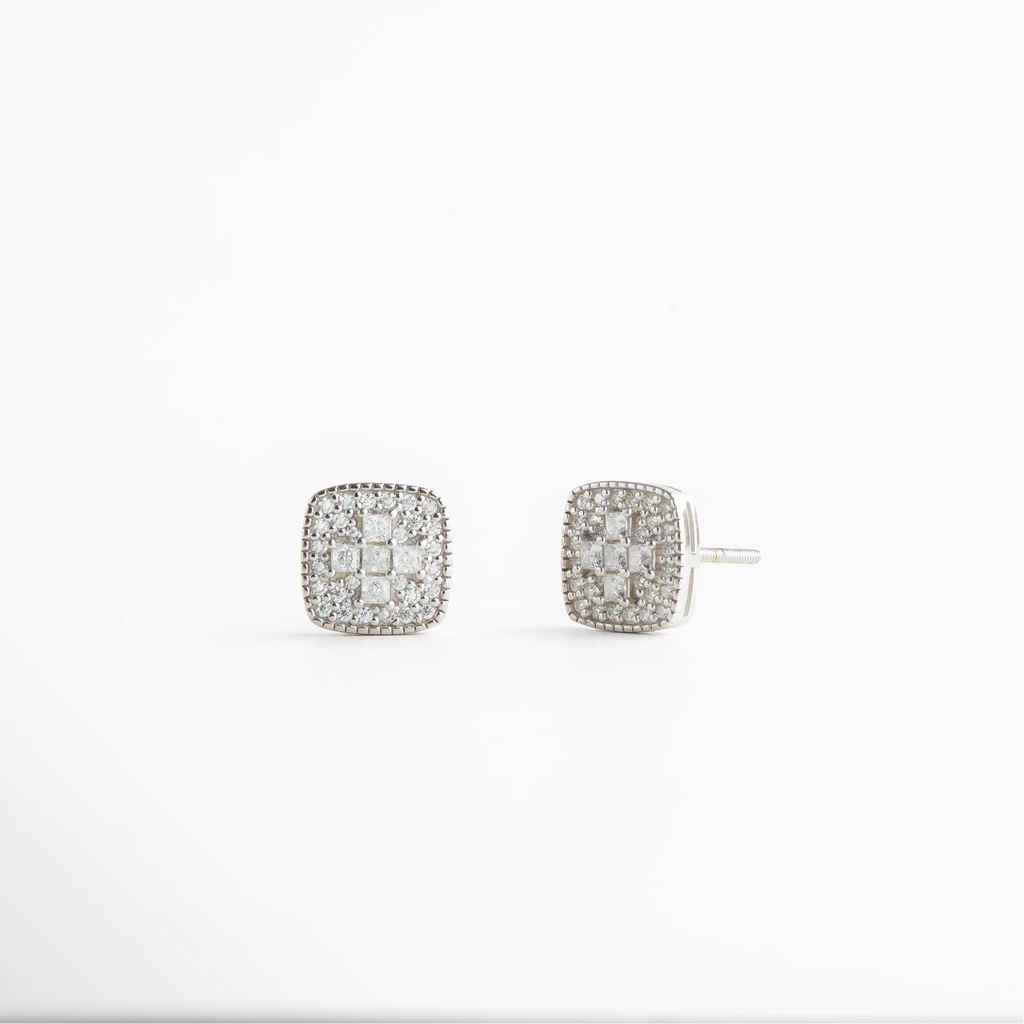 aretes stud con volumen sutil y proporciones equilibradas, detalle lateral del diseño cuadrado con brillo delicado, aretes pequeños que reflejan la luz suavemente, joyería minimal con presencia elegante, acabado limpio pensado para looks cotidianos