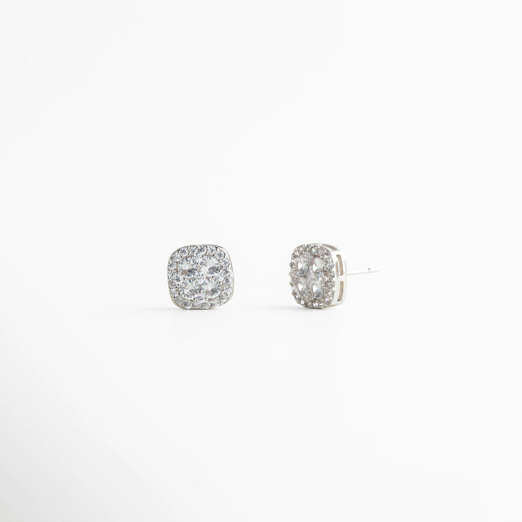 aretes plateados con volumen delicado, diseño geométrico de aretes con zirconias, aretes finos plateados con textura brillante, aretes pequeños elegantes con detalle pavé, joyería plateada femenina de líneas suaves, aretes stud con brillo uniforme