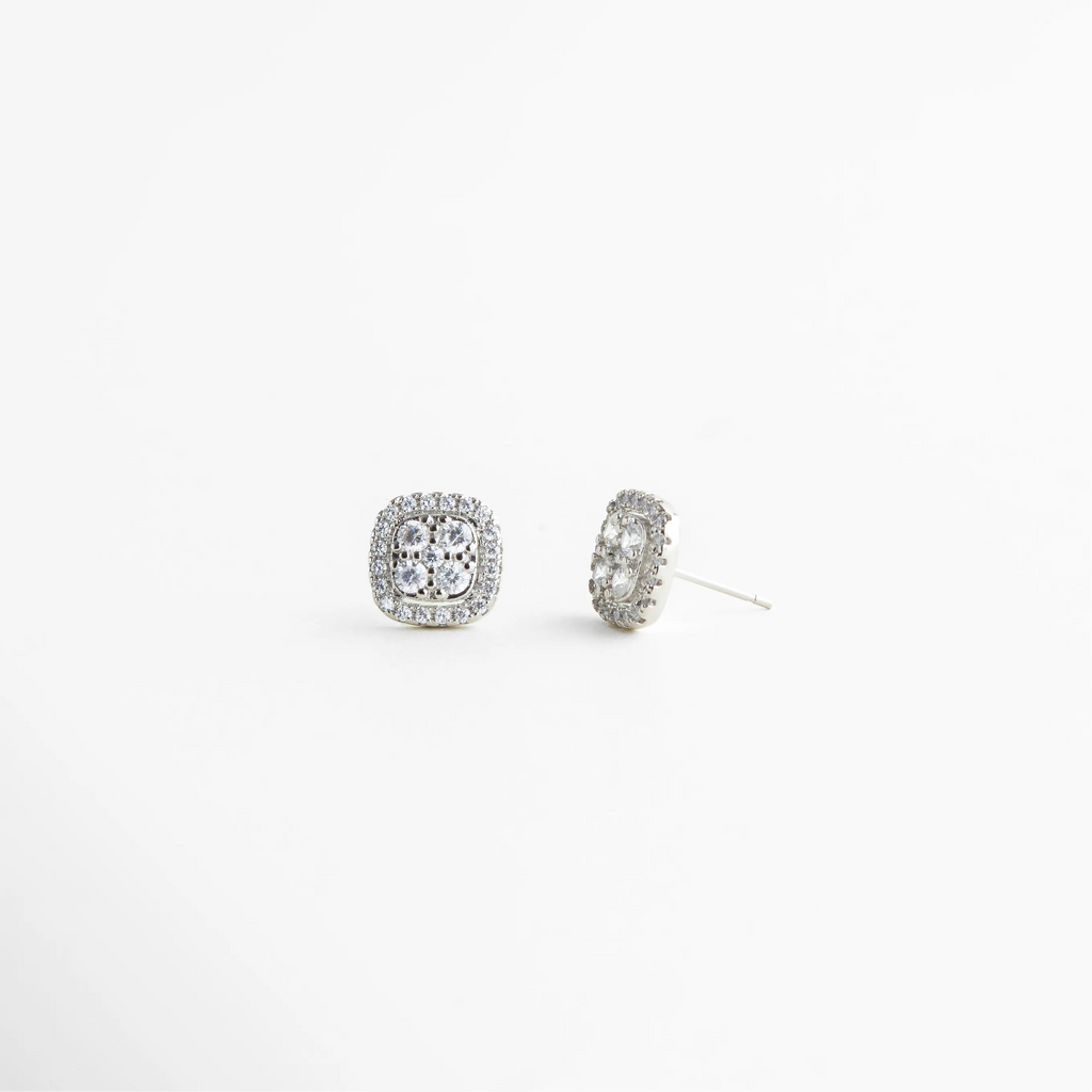Aretes plateados pequeños vistos en ángulo con textura brillante, Studs delicados plateados con zirconias desde vista lateral, Aretes minimalistas plateados con diseño cuadrado elegante, Aretes pequeños plateados para combinación en ear stack, Studs plateados con brillo suave y diseño atemporal, Aretes discretos plateados para uso diario