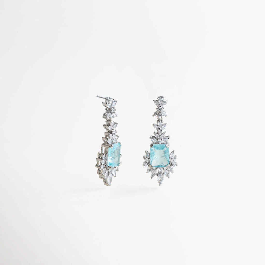 aretes azules vista frontal, joyería plateada elegante, aretes delicados con color, accesorios femeninos sofisticados, aretes largos elegantes, joyería brillante mujer, aretes chic de evento, joyería refinada