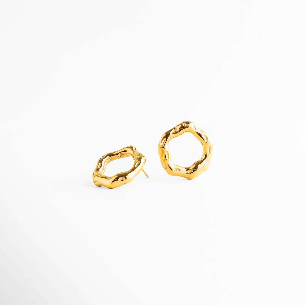 Aretes dorados vistos en par con forma orgánica, Studs circulares irregulares con acabado brillante, Aretes modernos de diseño escultórico, Aretes pequeños elegantes con volumen sutil, Joyería minimalista con formas fluidas