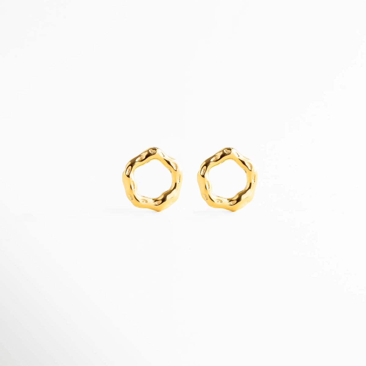 Arete stud mostrando grosor y volumen del diseño, Arete dorado con silueta irregular desde perfil, Detalle lateral de arete circular orgánico, Arete pequeño con diseño moderno tridimensional, Stud elegante con acabado pulido