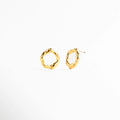 Aretes tipo stud con diseño circular irregular de acabado pulido, Aretes dorados de forma orgánica y estética moderna, Aretes pequeños con silueta abstracta y elegante, Studs dorados minimalistas con diseño artesanal, Aretes de aro irregular en joyería contemporánea
