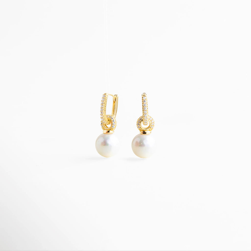 aretes con perla vista lateral y zirconias, aretes dorados con perla colgante perfil, aretes elegantes con perla lateral, aretes minimalistas con perla y brillo, aretes de joyería fina San Pedro Garza García