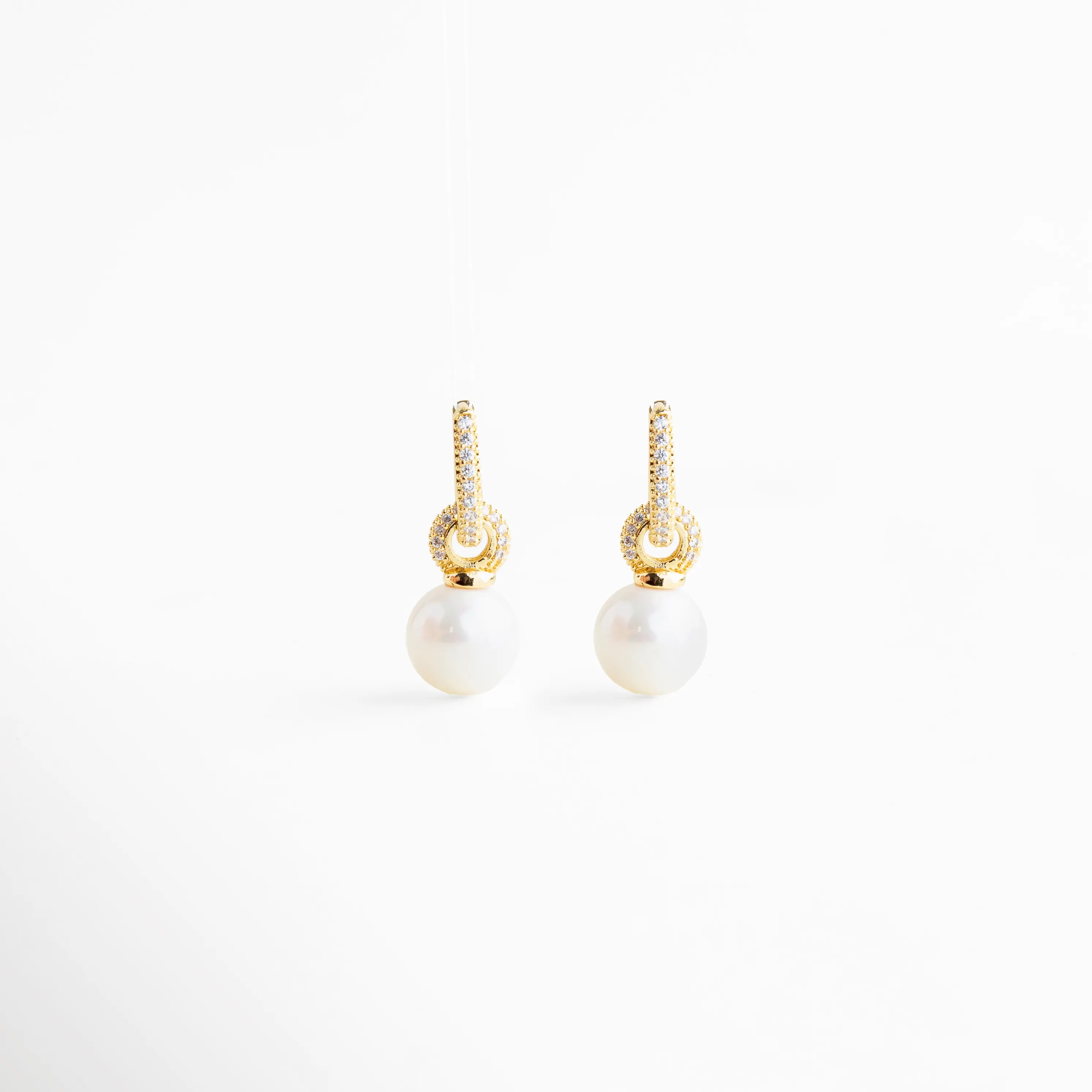 detalle de zirconias en aretes con perla, perla lisa colgante en aretes elegantes, acabado dorado en aretes con perla, textura y brillo de aretes con perla, detalle fino de joyería aretes Monterrey