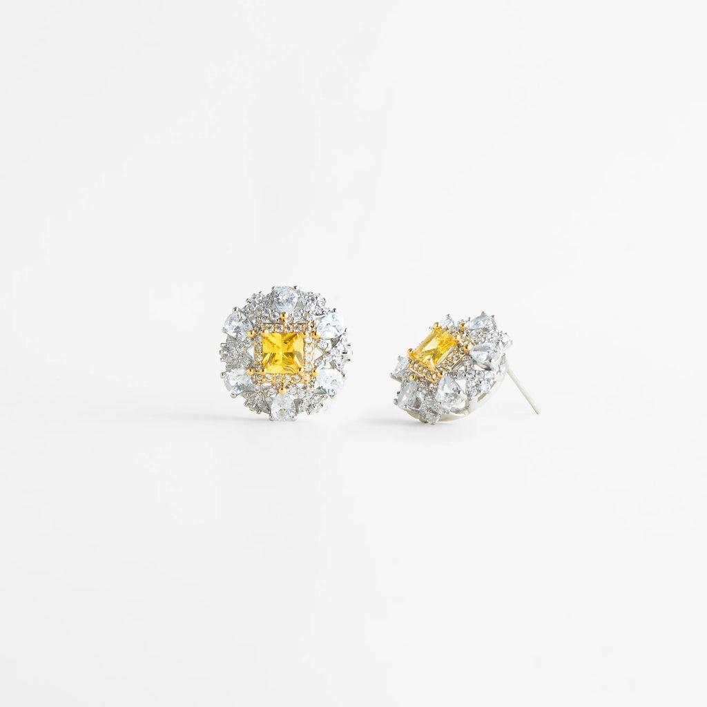 aretes plateados con piedra central amarilla brillante, aretes elegantes con zirconias y centro amarillo, aretes tipo stud con halo de zirconias plateadas, joyería fina con piedra amarilla enmarcada, aretes sofisticados con contraste plateado y amarillo, aretes clásicos con brillo intenso