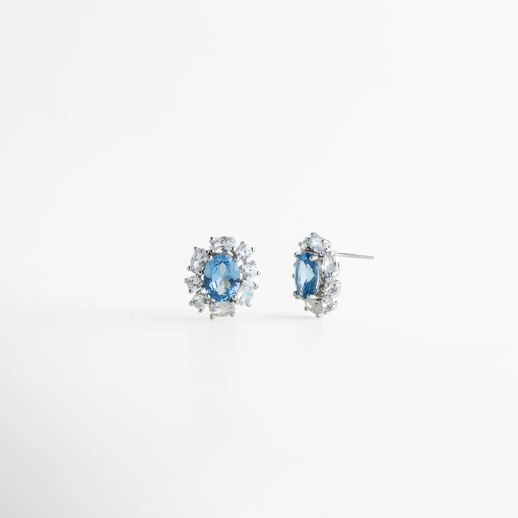 Aretes plateados con piedra azul vistos en ángulo, Studs elegantes con zirconias y montura plateada, Aretes pequeños de lujo con acabado brillante, Aretes clásicos con piedra azul y diseño refinado, Studs femeninos con detalles brillantes, Aretes delicados con estilo atemporal