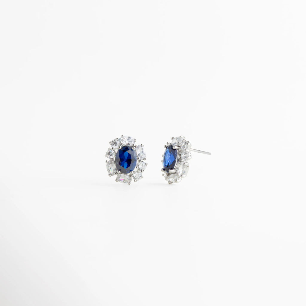 Aretes plateados con piedra azul oscuro vistos en ángulo, Studs elegantes con zirconias y gema azul profunda, Aretes clásicos con acabado plateado brillante, Aretes pequeños de lujo con piedra azul intensa, Studs femeninos con diseño atemporal, Aretes delicados con contraste profundo