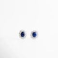 Aretes stud plateados con piedra azul oscuro y halo de zirconias, Aretes elegantes con gema azul profundo, Studs plateados clásicos con piedra azul intensa, Aretes pequeños con zirconias y diseño sofisticado, Aretes finos plateados con brillo profundo, Aretes elegantes con piedra azul oscuro central