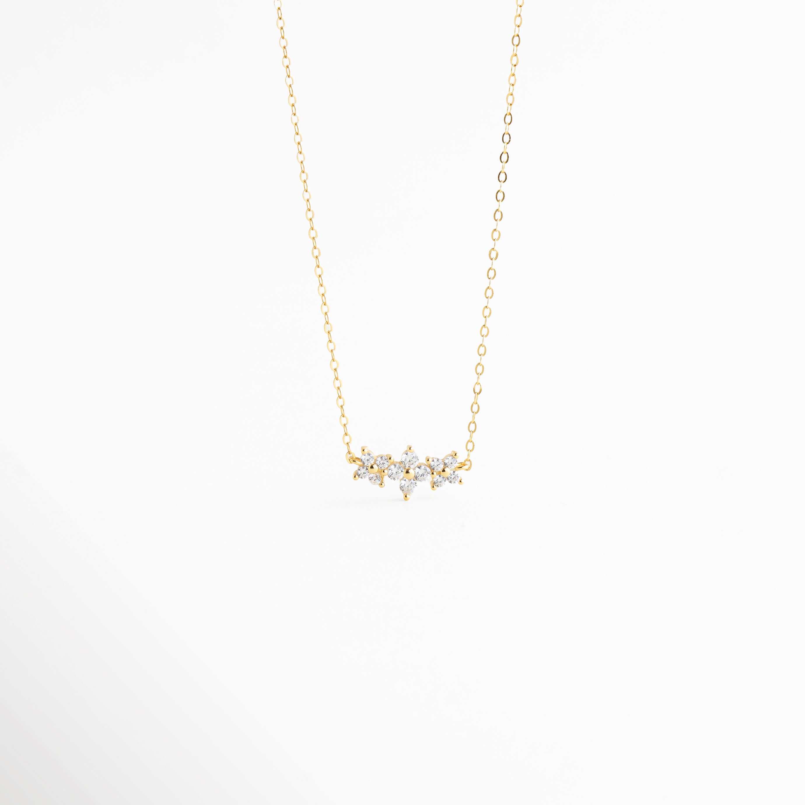 Collar de Plata 925 con baño de oro 18K y dije de flores con circonias brillantes, Gargantilla dorada fina con colgante de cristales en forma de racimo floral, Vista frontal de collar minimalista en oro con incrustaciones de circonia transparente, Joyería de plata ley 925: collar con dije de 1.5 cm decorado con piedras brillantes, Collar elegante con cadena delgada y motivo floral de circonias para mujer.