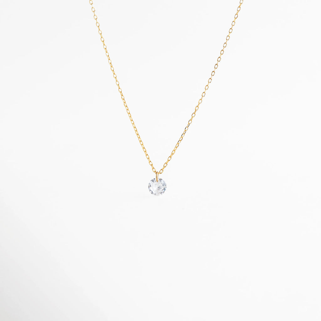 Collar solitario de Plata 925 con baño de oro y una brillante piedra de zirconia central, Collar fino dorado con dije de "punto de luz" en zirconia cúbica transparente, Vista detallada de collar minimalista con cristal brillante y cadena de plata dorada, Joyería clásica: collar de un solo brillante con acabado en oro sobre plata de ley, Colgante solitario redondo de zirconia con cadena delgada, estilo "delicate gold necklace.
