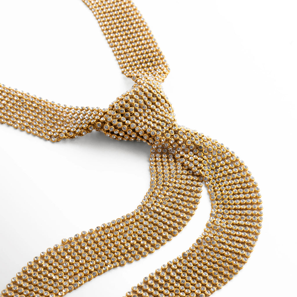 detalle de unión tipo nudo en collar dorado corbatín
conexión central en collar de malla dorada elegante
diseño estructural en collar tipo corbata dorado
punto focal en collar statement de malla dorada
detalle central decorativo en collar moderno dorado