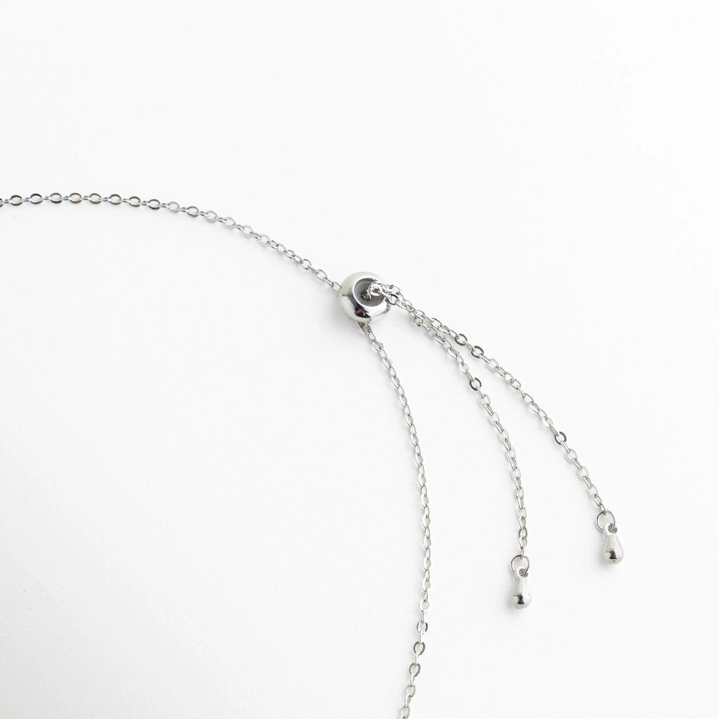 broche de collar lariat plateado, detalle de cadena fina plateada, collar elegante con cierre discreto, joyería fina con acabado brillante, collar plateado de alta calidad, collar lariat moderno y versátil
