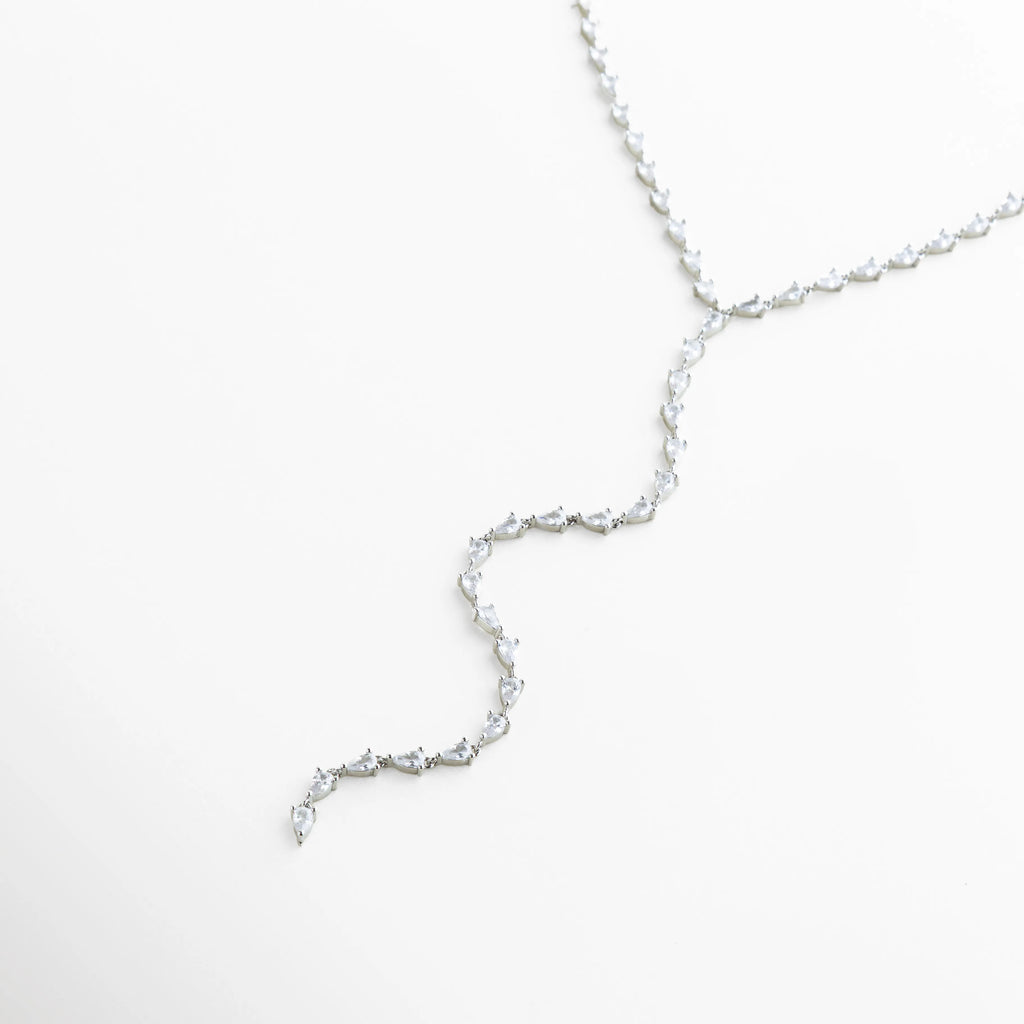 collar lariat plateado vista lateral, perfil del collar largo elegante, joyería fina collar de líneas suaves, collar plateado con estructura fluida, diseño ligero de collar lariat, collar sofisticado para uso diario o eventos