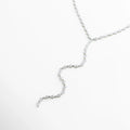 collar lariat plateado vista lateral, perfil del collar largo elegante, joyería fina collar de líneas suaves, collar plateado con estructura fluida, diseño ligero de collar lariat, collar sofisticado para uso diario o eventos
