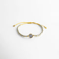 Pulsera ajustable con hilo y cuentas en oro y oro blanco 18K, diseño elegante, Pulsera artesanal de cobre con recubrimiento en oro 18K y detalle central, Pulsera fina con hilo ajustable y cuentas metálicas en acabado dorado, Pulsera elegante con combinación de oro y oro blanco, estilo minimalista, Pulsera ajustable para mujer con diseño delicado y acabado brillante