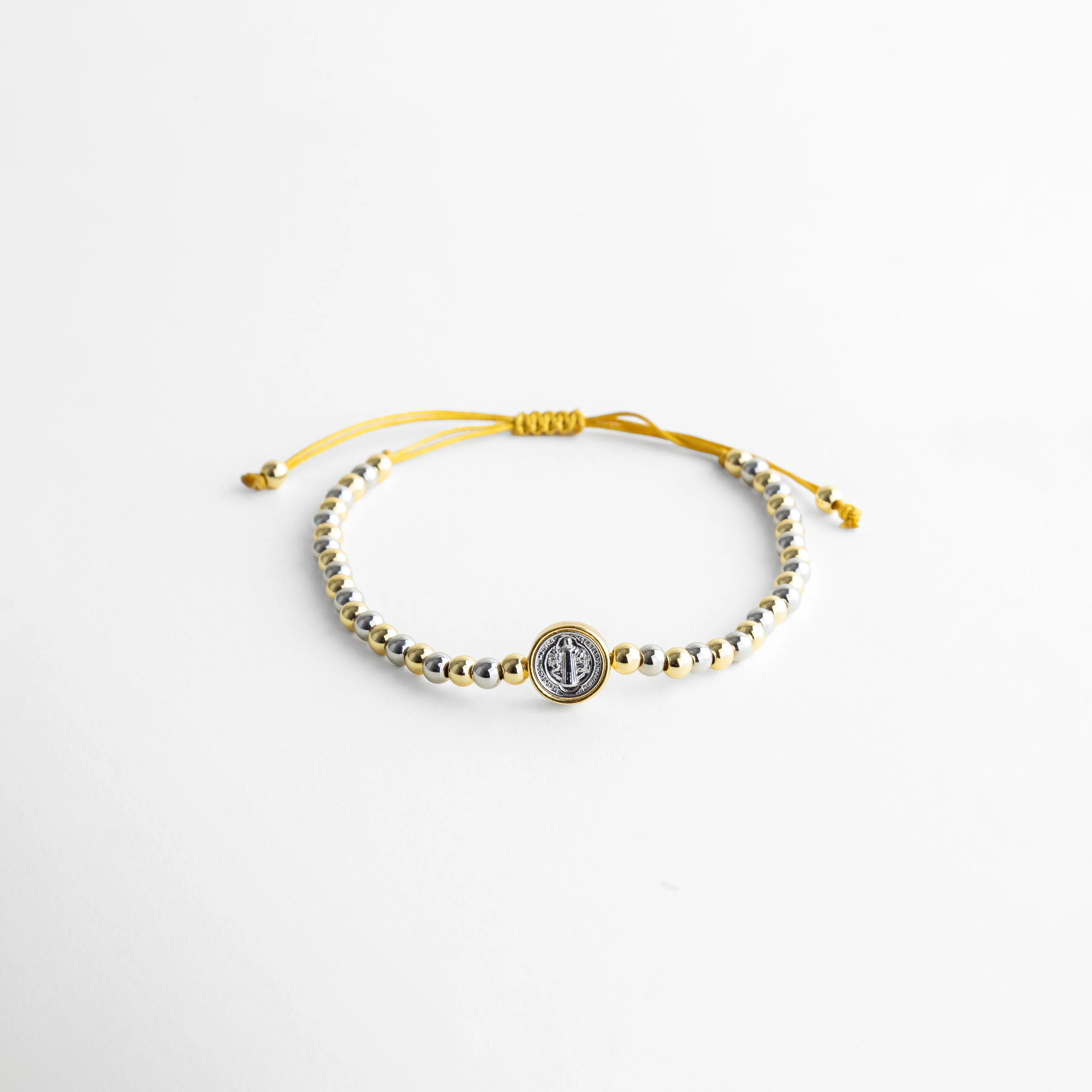 Pulsera ajustable con hilo y cuentas en oro y oro blanco 18K, diseño elegante, Pulsera artesanal de cobre con recubrimiento en oro 18K y detalle central, Pulsera fina con hilo ajustable y cuentas metálicas en acabado dorado, Pulsera elegante con combinación de oro y oro blanco, estilo minimalista, Pulsera ajustable para mujer con diseño delicado y acabado brillante