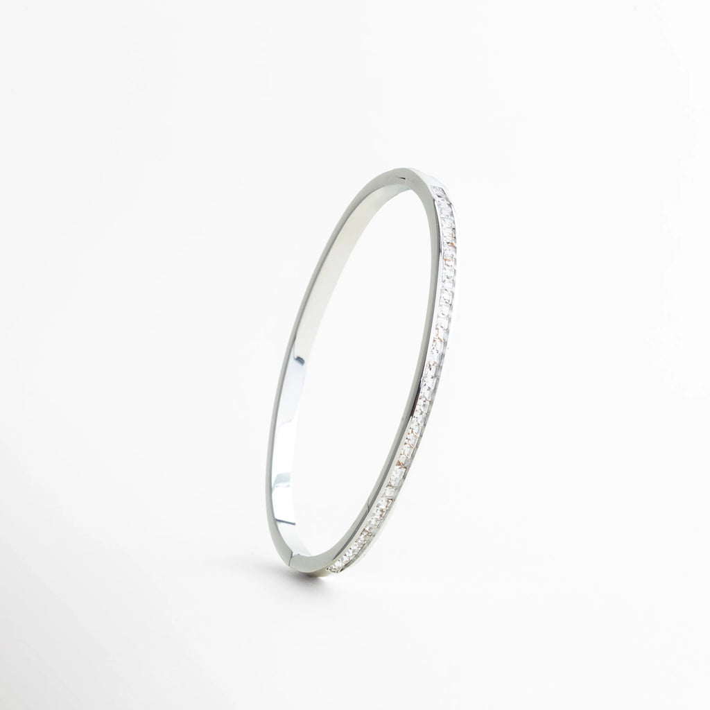 pulsera plateada vista lateral perfil delgado, pulsera rígida elegante vista de costado, pulsera fina con zirconias engastadas, pulsera minimalista joyería plateada, pulsera estilizada vista lateral, pulsera sofisticada de perfil delgado