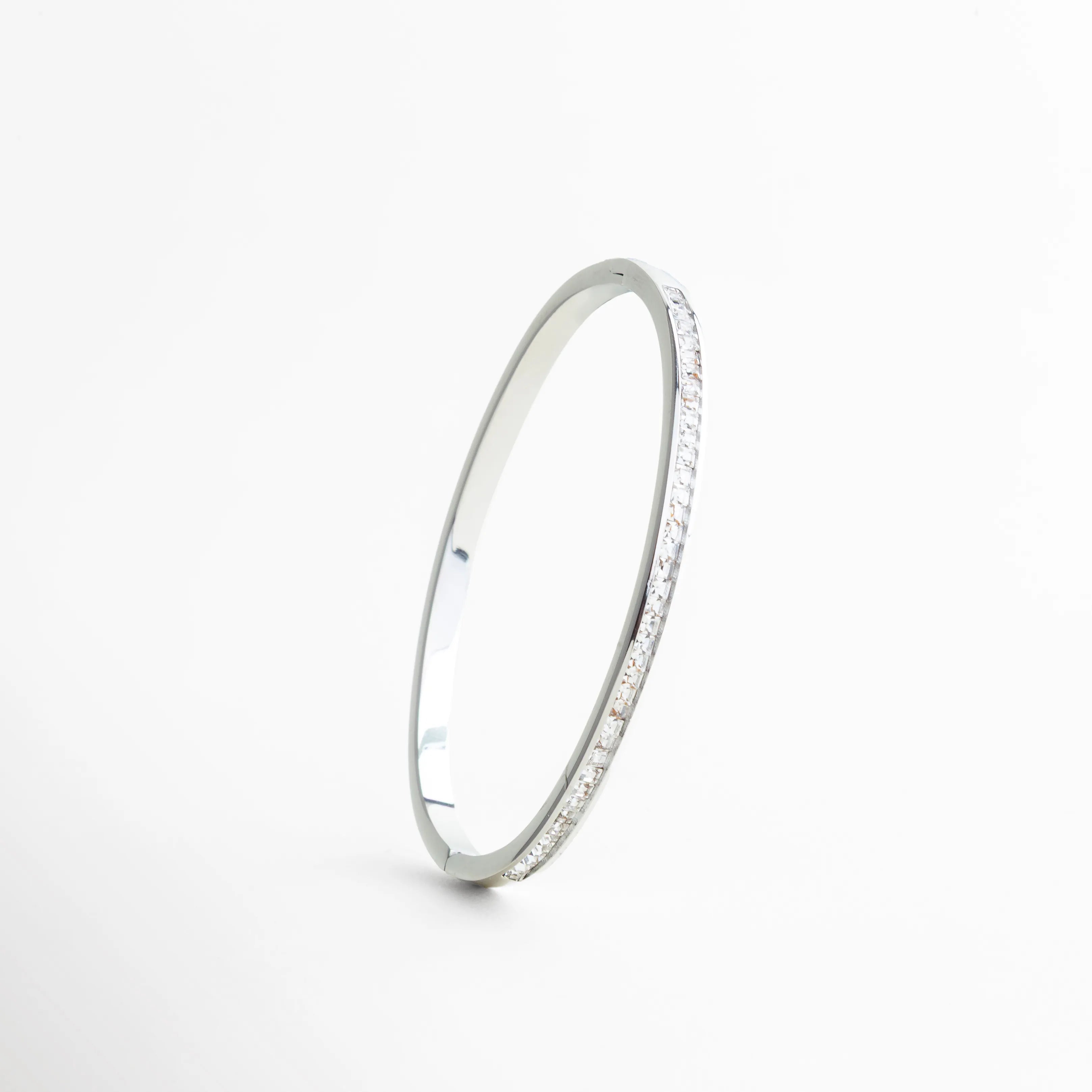 pulsera plateada vista lateral perfil delgado, pulsera rígida elegante vista de costado, pulsera fina con zirconias engastadas, pulsera minimalista joyería plateada, pulsera estilizada vista lateral, pulsera sofisticada de perfil delgado