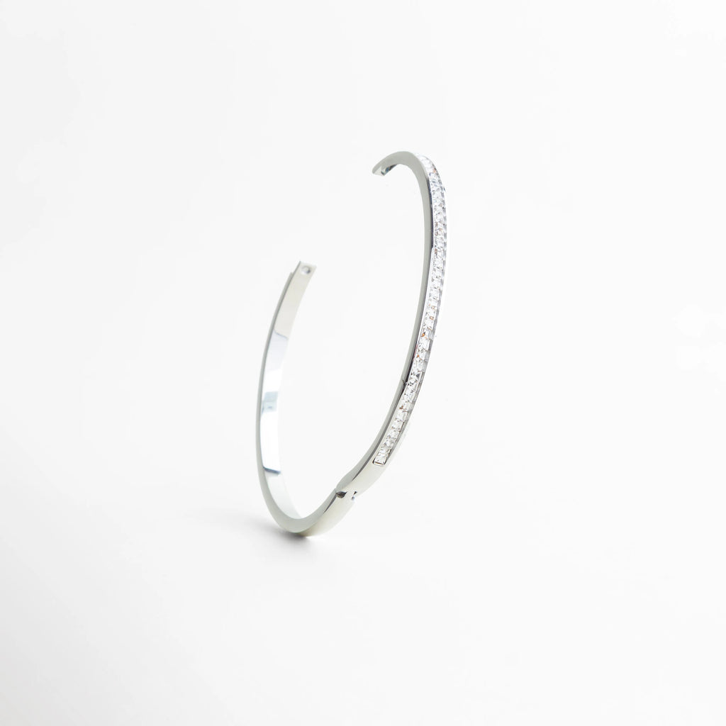 pulsera plateada vista en ángulo elegante, pulsera rígida con brillo sutil, pulsera de zirconias diseño moderno, pulsera minimal vista diagonal, pulsera elegante joyería contemporánea, pulsera plateada con acabado pulido
