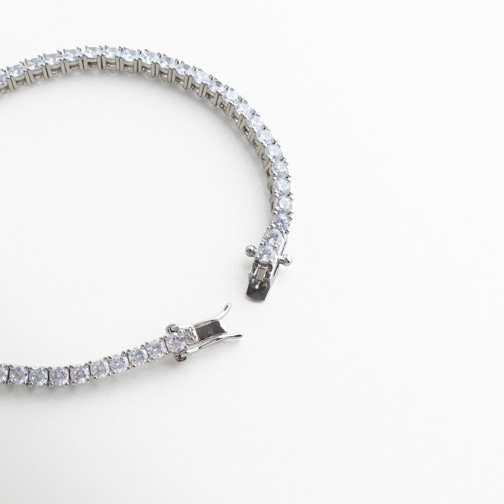pulsera tennis broche, detalle cierre pulsera, joyería plateada fina, pulsera elegante con cierre, accesorios sofisticados mujer, pulsera clásica chic, joyería luminosa plateada, pulsera de diseño elegante