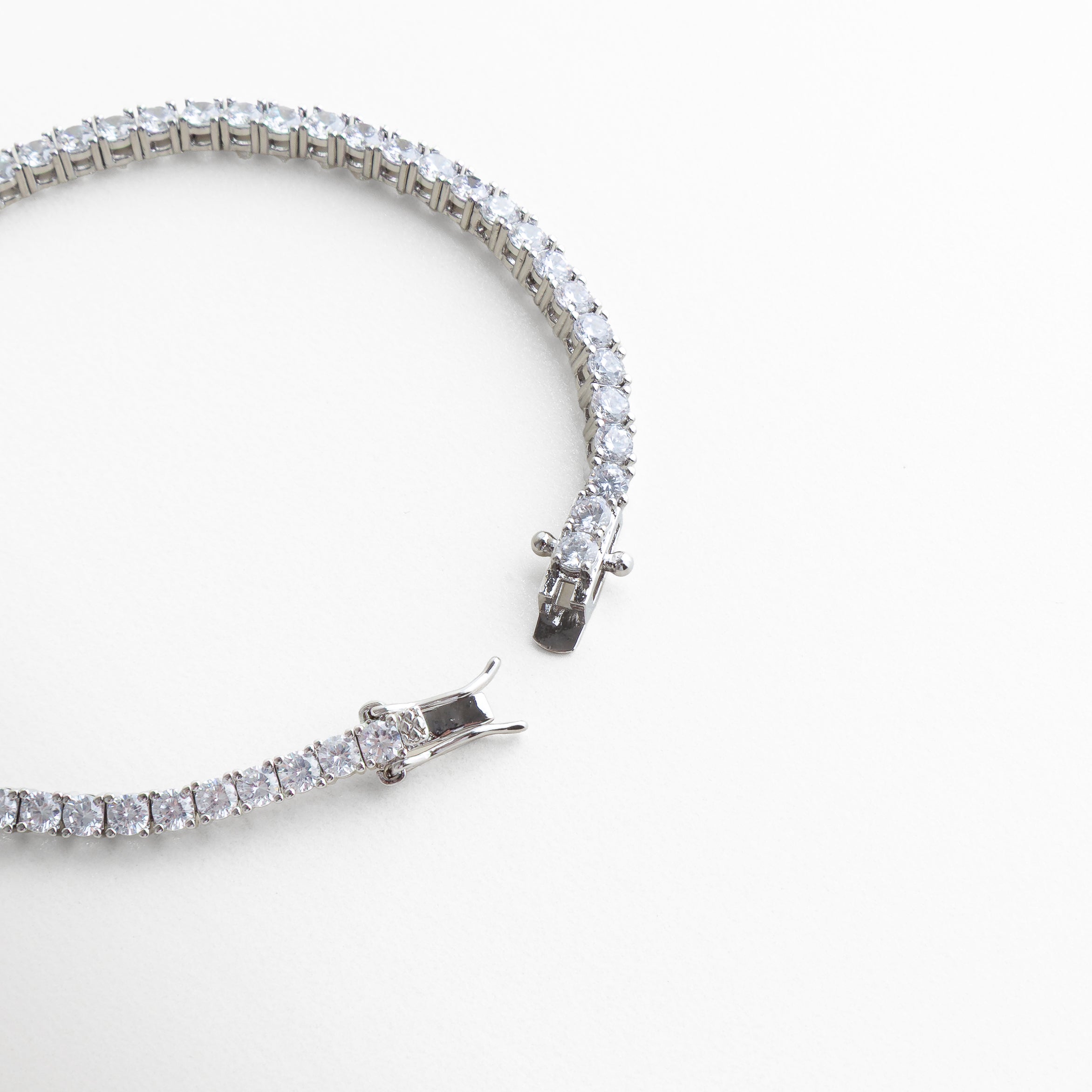 pulsera tennis broche, detalle cierre pulsera, joyería plateada fina, pulsera elegante con cierre, accesorios sofisticados mujer, pulsera clásica chic, joyería luminosa plateada, pulsera de diseño elegante