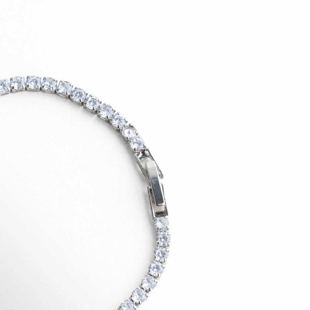 pulsera tennis broche, detalle cierre pulsera, joyería plateada fina, pulsera elegante con cierre, accesorios sofisticados mujer, pulsera clásica chic, joyería femenina luminosa, pulsera de diseño elegante