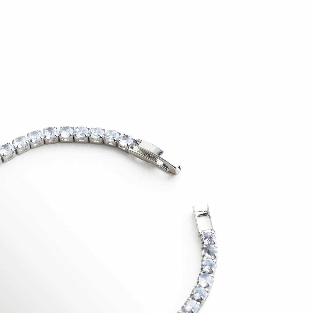 pulsera tennis detalle, pulsera plateada con cristales, joyería elegante femenina, pulsera con brillo continuo, detalle broche pulsera, joyería plateada sofisticada, pulsera fina mujer, joyería luminosa