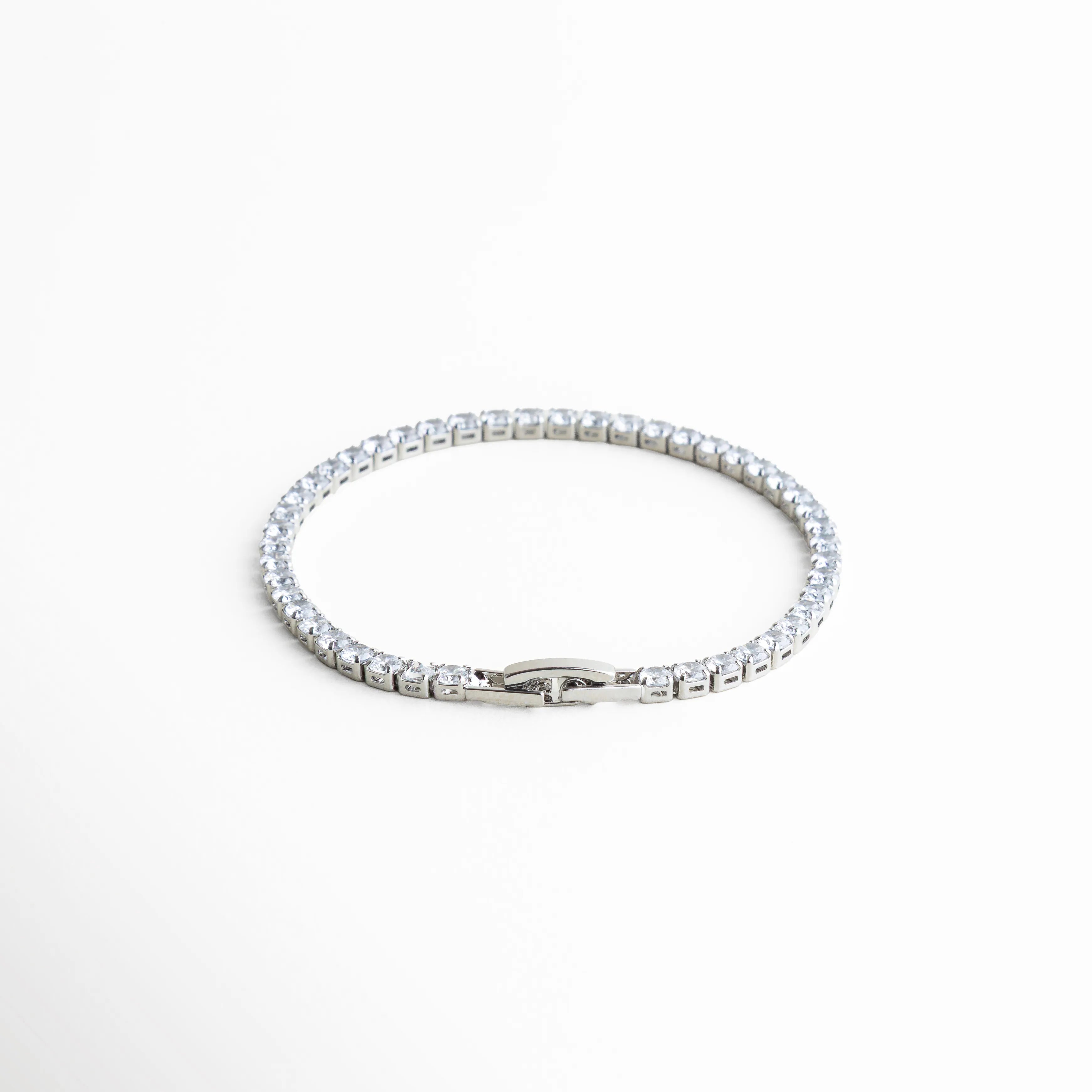 pulsera tennis vista superior, pulsera elegante plateada, joyería clásica moderna, pulsera femenina atemporal, accesorios plateados chic, pulsera con piedras brillantes, joyería delicada mujer, pulsera refinada