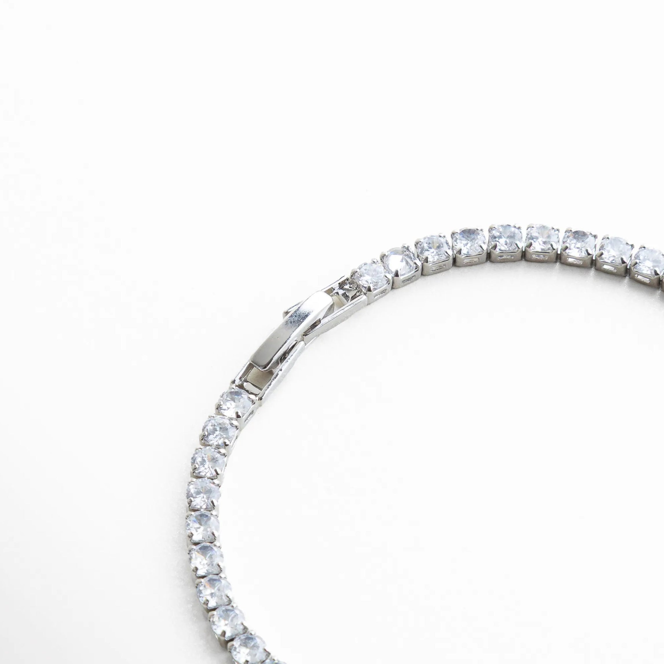 detalle pulsera tennis, pulsera con piedras alineadas, joyería plateada moderna, pulsera con brillo delicado, accesorios elegantes mujer, joyería luminosa plateada, pulsera de diseño fino, pulsera sofisticada