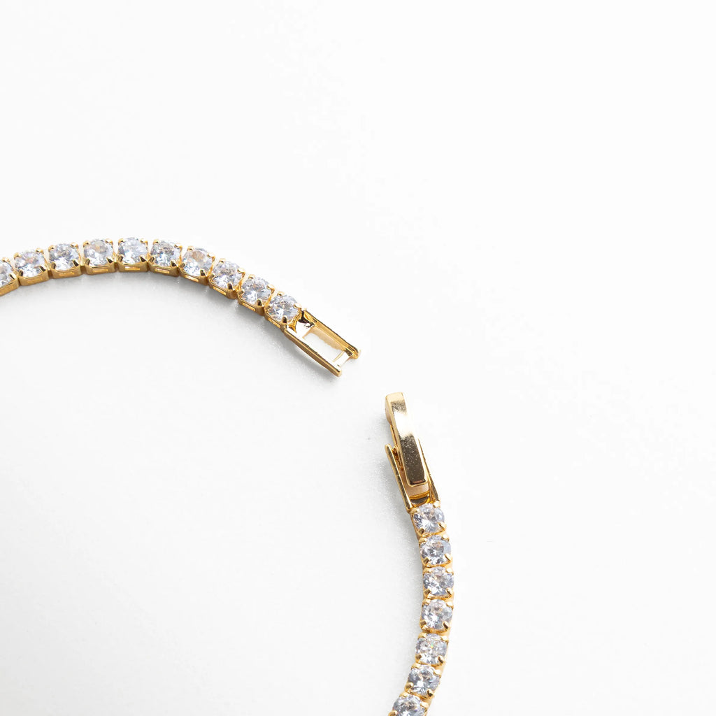 pulsera tennis dorada detalle, pulsera dorada con cristales, joyería dorada elegante, pulsera con brillo continuo, detalle broche pulsera, joyería sofisticada mujer, pulsera fina dorada, joyería luminosa