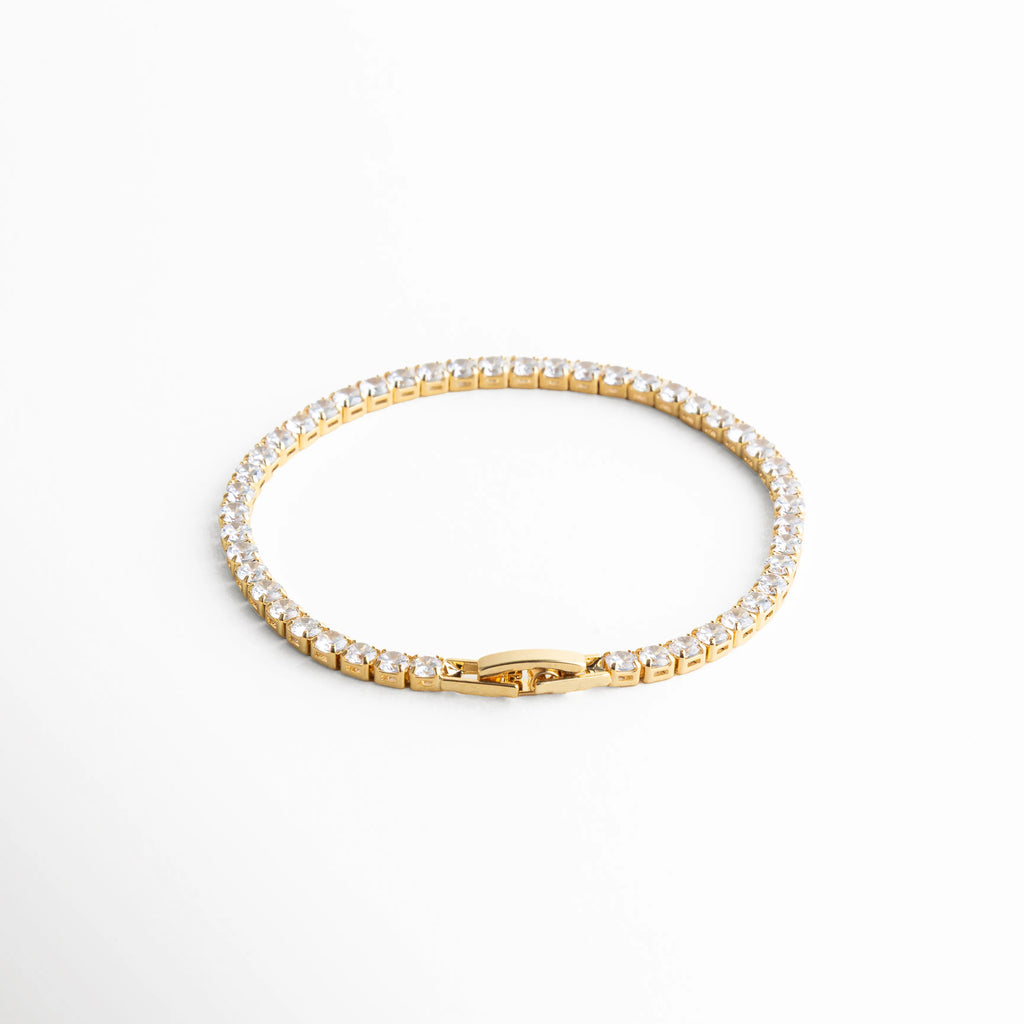 pulsera tennis dorada vista superior, pulsera elegante dorada, joyería clásica moderna, pulsera femenina atemporal, accesorios dorados chic, pulsera con piedras brillantes, joyería delicada mujer, pulsera refinada