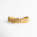 Pulsera rígida dorada con textura orgánica y cristales incrustados, una pieza moderna y escultural que resalta en cualquier look.