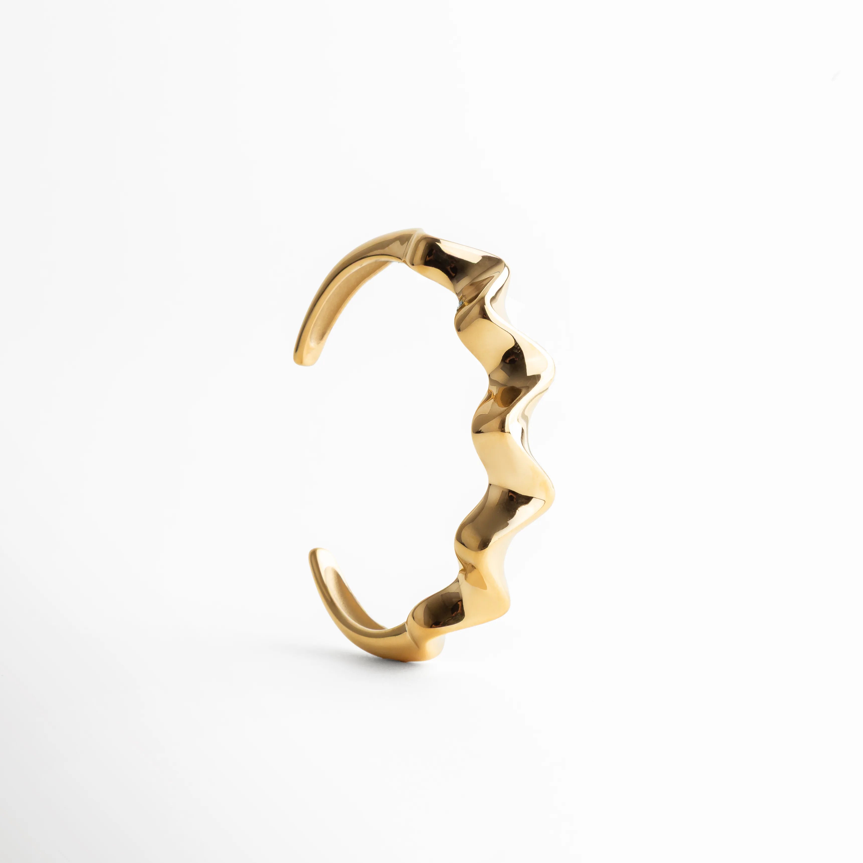 pulsera dorada ondulada, pulsera escultórica, joyería dorada moderna, pulsera statement minimal, accesorios dorados elegantes, pulsera de diseño, joyería contemporánea, pulsera sofisticada